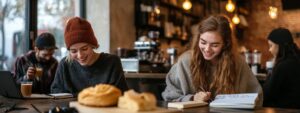 Two students enjoying coffee while smiling and studying together