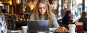 Young woman in a café studying with a laptop and breakfast.
