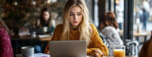 Blonde college student focused on her laptop while studying at a café