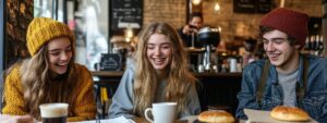 Group of college students laughing over coffee and notes in a café