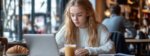 Focused student in a cafe working on laptop with breakfast