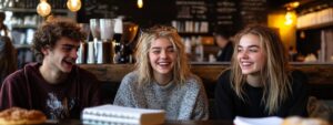 Three college students laughing together in a café.